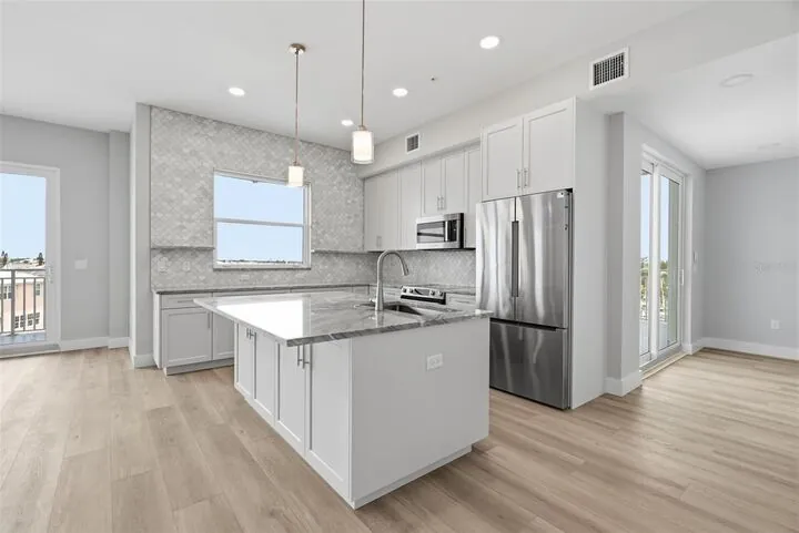 White kitchen with a stone-topped island and stainless appliances